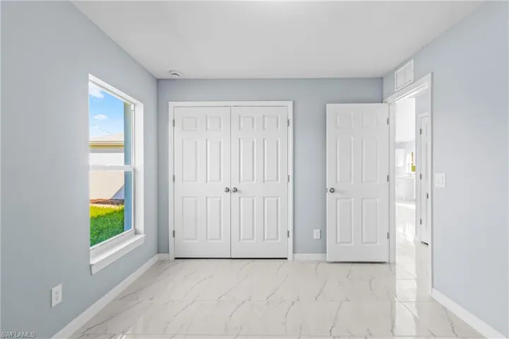 Unfurnished bedroom with light marble finish flooring and a closet