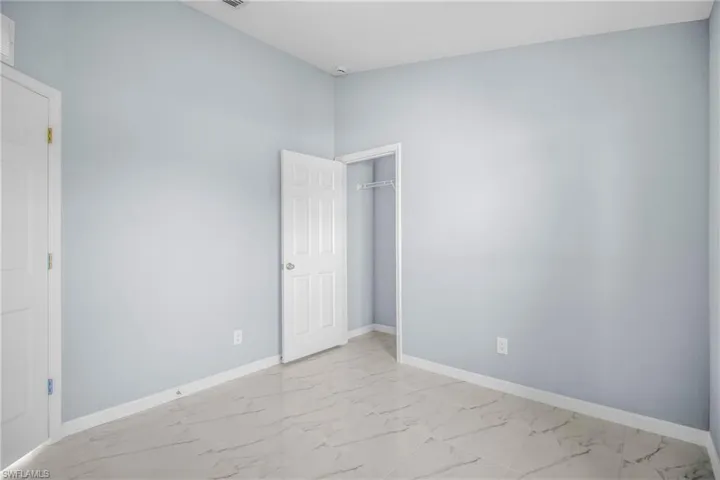 Unfurnished bedroom featuring light marble finish floors and a closet
