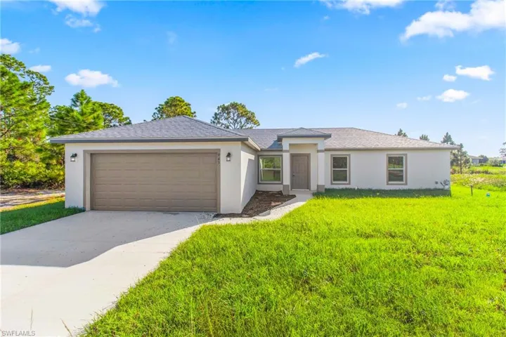 Prairie-style home with stucco siding, concrete driveway, a front lawn, and an attached garage