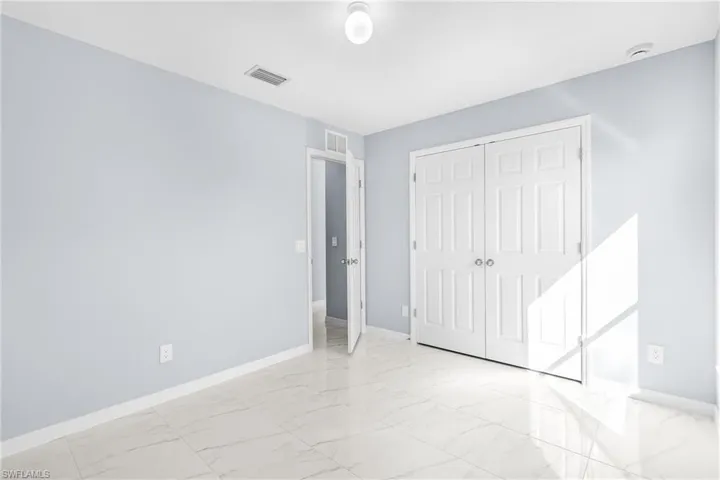 Unfurnished bedroom featuring light marble finish floors and a closet
