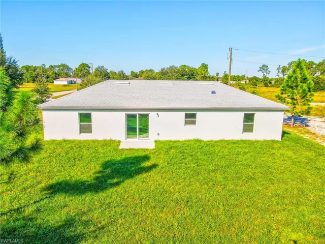 Back of property with a lawn and stucco siding