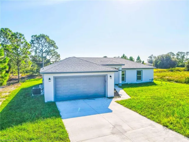Ranch-style house with stucco siding, a front lawn, concrete driveway, a shingled roof, and an attached garage