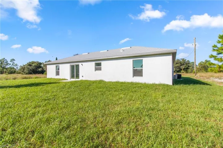 Back of property featuring a lawn and stucco siding