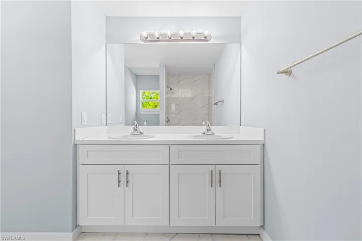 Full bathroom with double vanity, a marble finish shower, and light marble finish floors