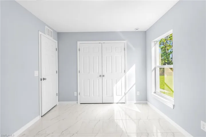 Unfurnished bedroom featuring light marble finish flooring and a closet