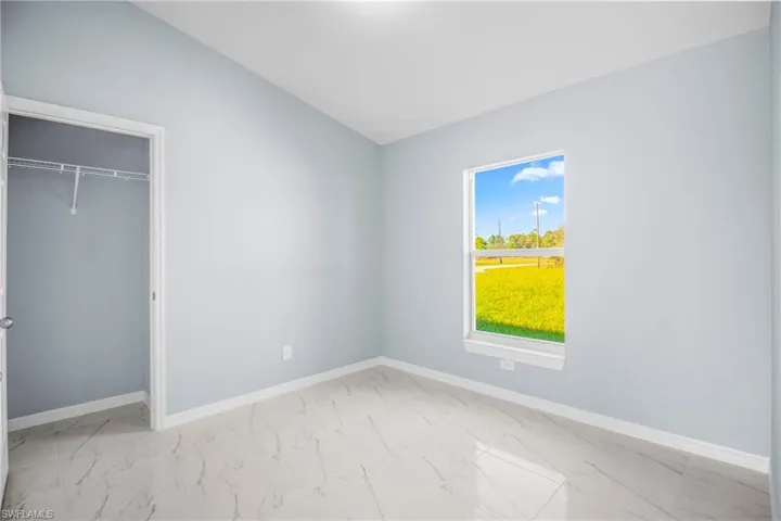 Unfurnished bedroom with light marble finish flooring, a closet, and vaulted ceiling