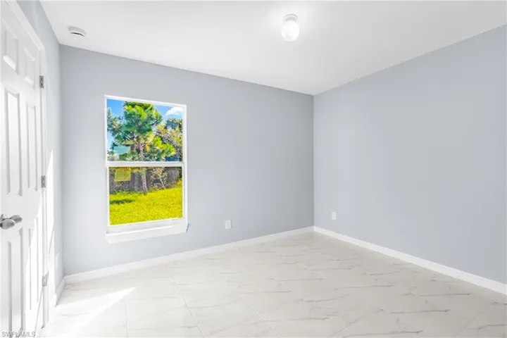 Empty room featuring light marble finish floors and baseboards