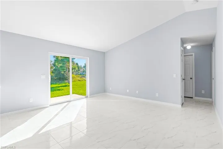 Spare room with light marble finish flooring and vaulted ceiling