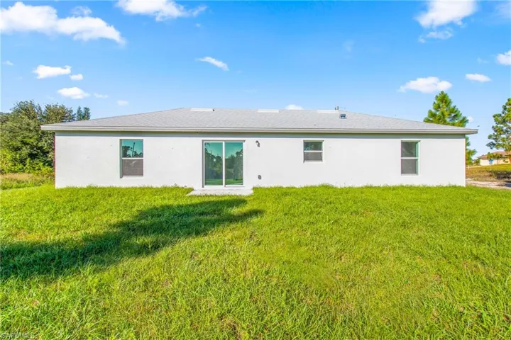 Back of property featuring a lawn and stucco siding