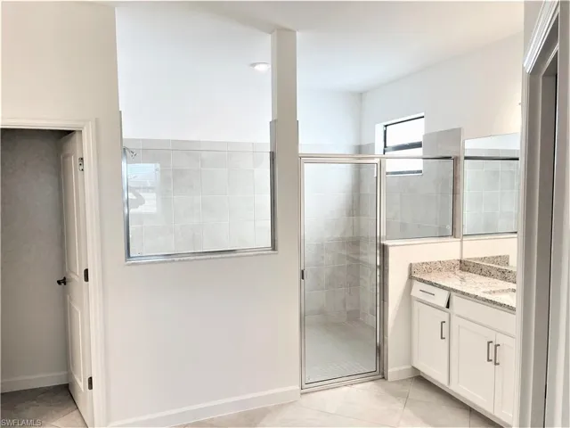 Full bath with a shower stall, vanity, and light tile patterned floors