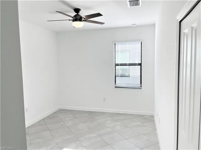 Empty room featuring ceiling fan and light tile patterned floors