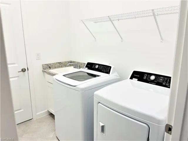Laundry room with washing machine and dryer and light tile patterned floors