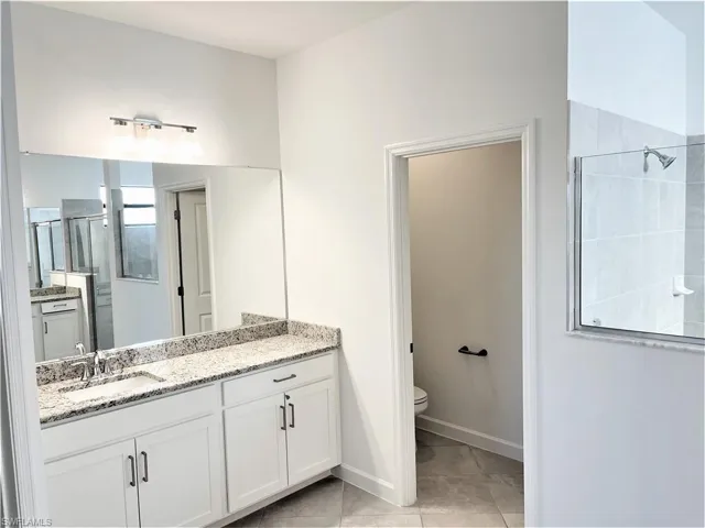 Bathroom featuring a shower stall, vanity, and light tile patterned flooring