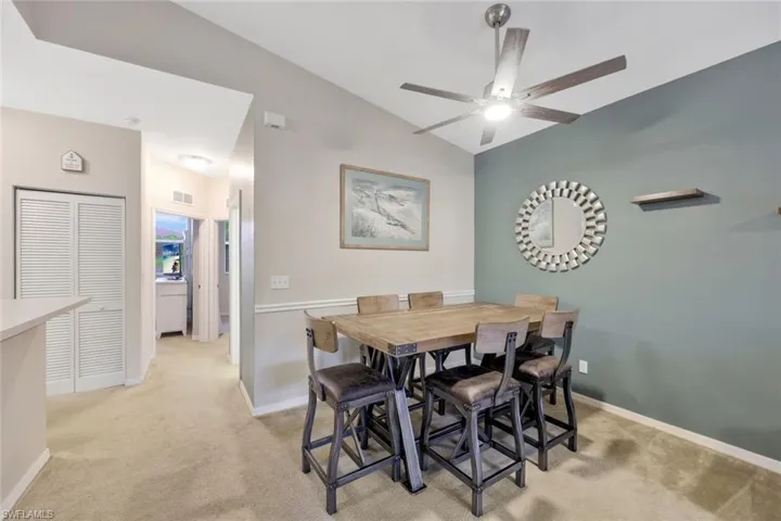 Dining area featuring vaulted ceiling, light carpet, and ceiling fan