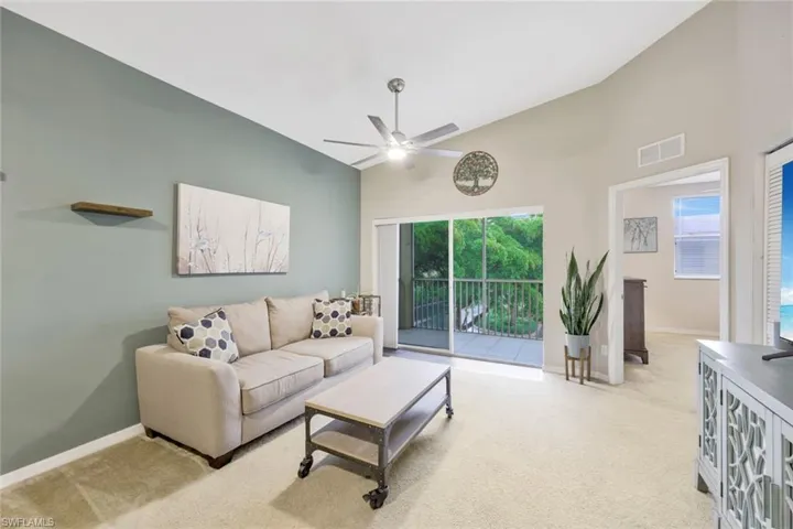 Living room with high vaulted ceiling, ceiling fan, and carpet floors