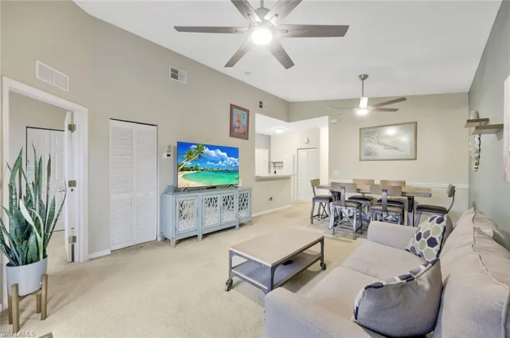 Carpeted living room with vaulted ceiling and ceiling fan