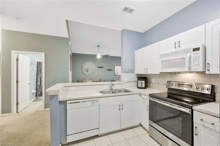Kitchen with white cabinetry, white appliances, and kitchen peninsula