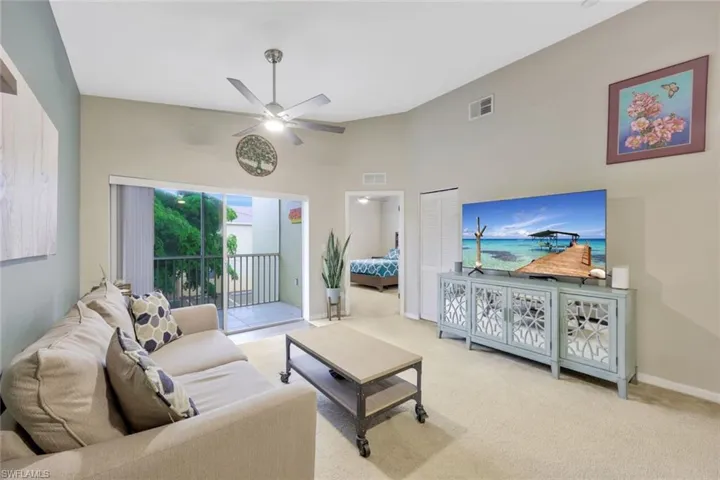 Carpeted living room with ceiling fan and a towering ceiling