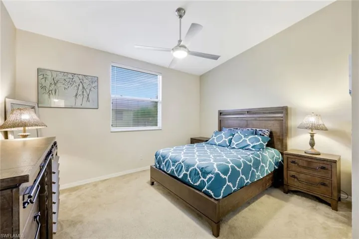 Carpeted bedroom with ceiling fan and lofted ceiling