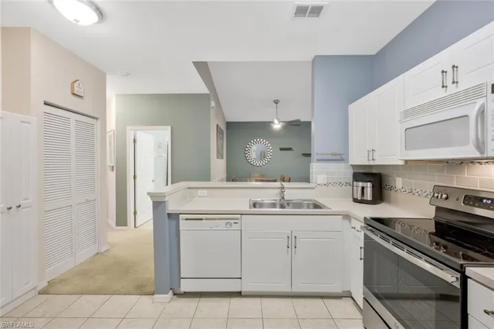 Kitchen with white appliances, sink, and white cabinets