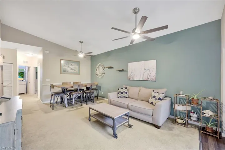 Carpeted living room with ceiling fan and lofted ceiling
