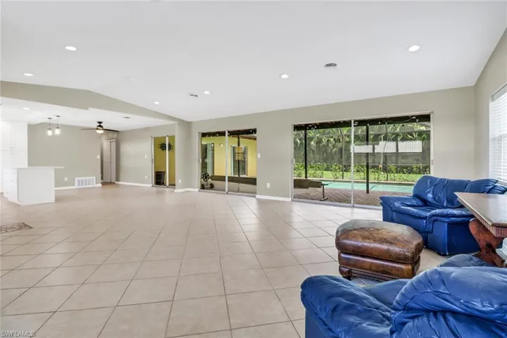 Tiled living room with ceiling fan, a healthy amount of sunlight, and vaulted ceiling