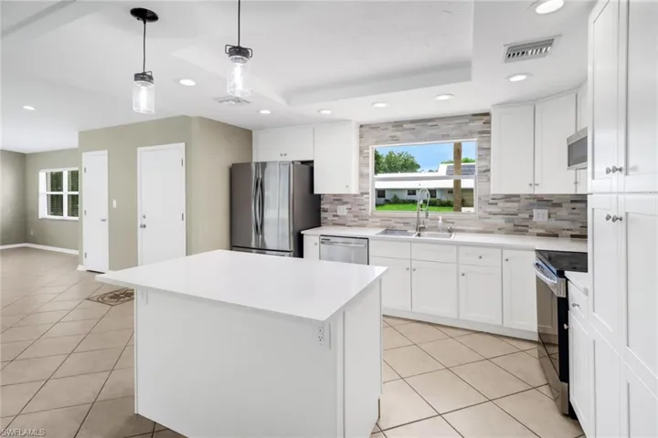 Kitchen with white cabinetry, sink, a center island, and stainless steel appliances