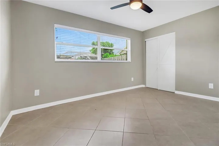 Unfurnished bedroom featuring light tile patterned floors and ceiling fan