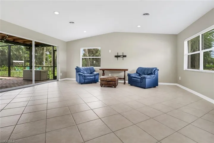 Living area with light tile patterned floors, vaulted ceiling, and plenty of natural light