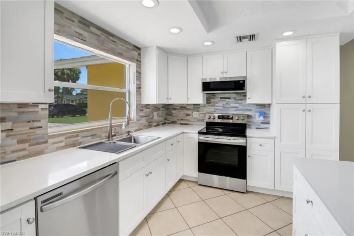 Kitchen featuring white cabinetry, sink, light tile patterned floors, and stainless steel appliances