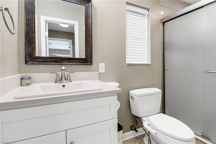 Bathroom with an enclosed shower, vanity, and toilet