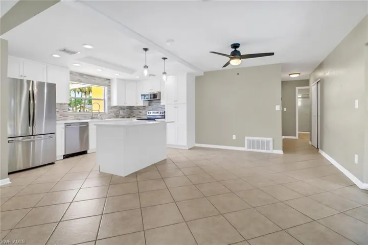 Kitchen featuring white cabinetry, a center island, hanging light fixtures, light tile patterned floors, and appliances with stainless steel finishes