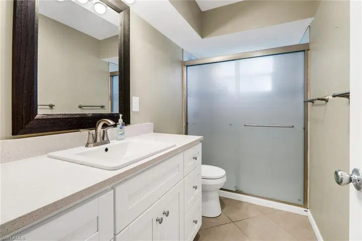 Bathroom featuring tile patterned floors, vanity, toilet, and walk in shower