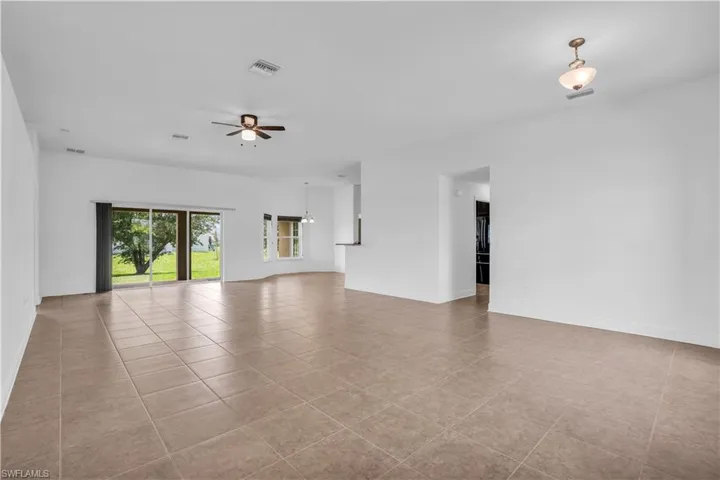 Unfurnished living room with light tile patterned floors and ceiling fan