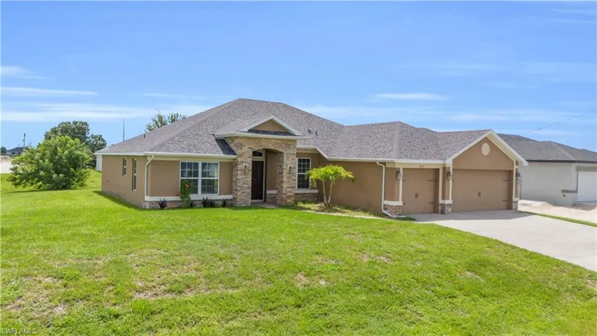 View of front of property featuring a garage and a front lawn