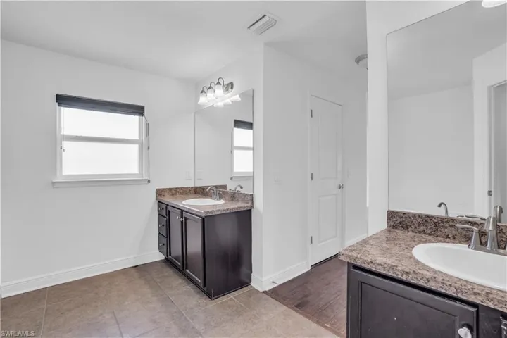 Bathroom featuring tile patterned flooring, dual bowl vanity, and a healthy amount of sunlight