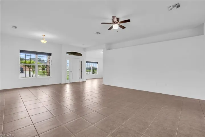 Tiled spare room featuring plenty of natural light and ceiling fan