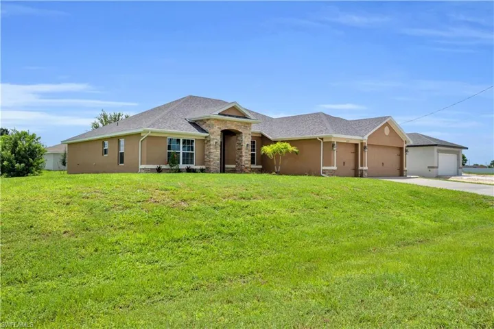 Ranch-style house featuring a garage and a front lawn