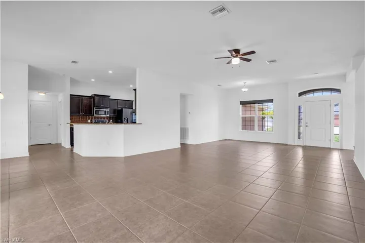 Unfurnished living room with light tile patterned floors and ceiling fan