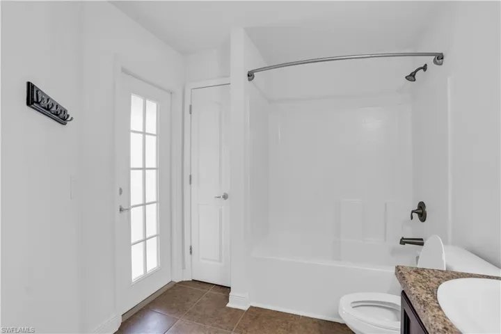 Full bathroom with  shower combination, tile patterned floors, toilet, and plenty of natural light