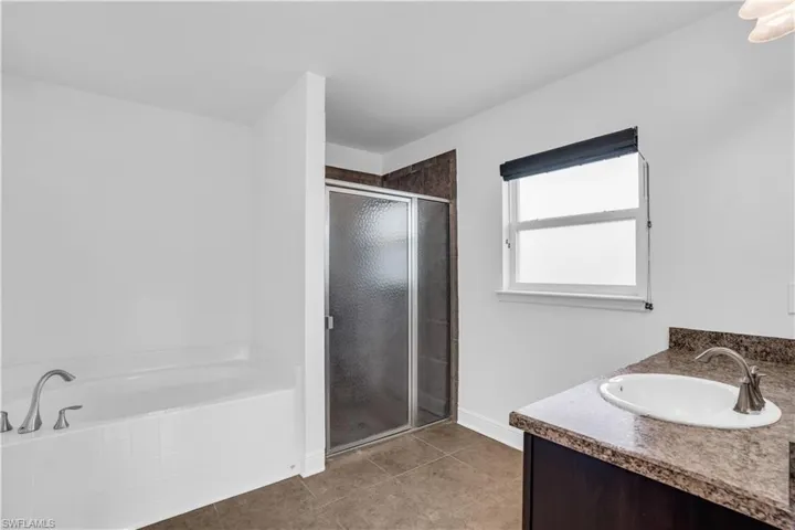 Bathroom with independent shower and bath, vanity, and tile patterned floors