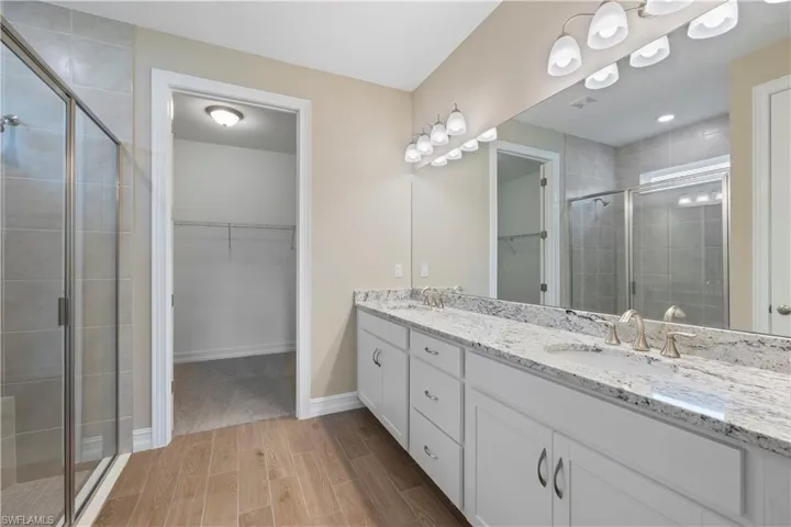 Bathroom featuring wood-type flooring, double sink vanity, and walk in shower