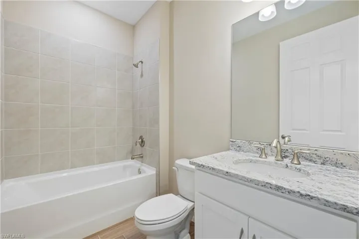 Full bathroom with vanity, tiled shower / bath, and toilet
