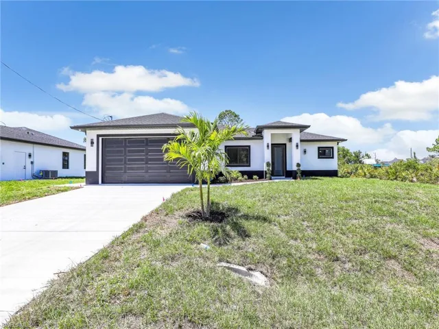 Prairie-style home with concrete driveway, a front yard, a garage, and stucco siding