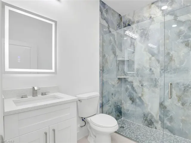 Bathroom featuring vanity and a marble finish shower