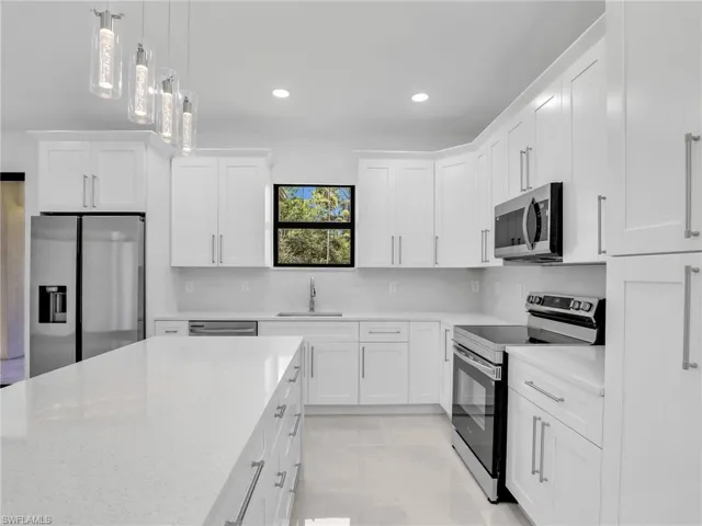 Kitchen featuring appliances with stainless steel finishes, decorative light fixtures, white cabinets, recessed lighting, and backsplash