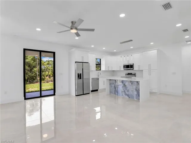 Kitchen with stainless steel appliances, hanging light fixtures, recessed lighting, white cabinets, and plenty of natural light
