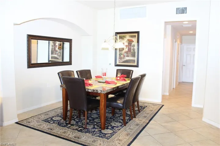 Dining room with light tile patterned flooring, baseboards, visible vents, and a chandelier