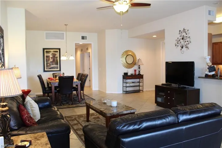 Living room with light tile patterned flooring, ceiling fan, and visible vents
