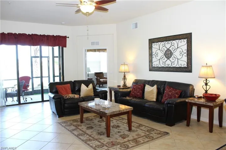 Living room with light tile patterned floors, plenty of natural light, ceiling fan, and visible vents